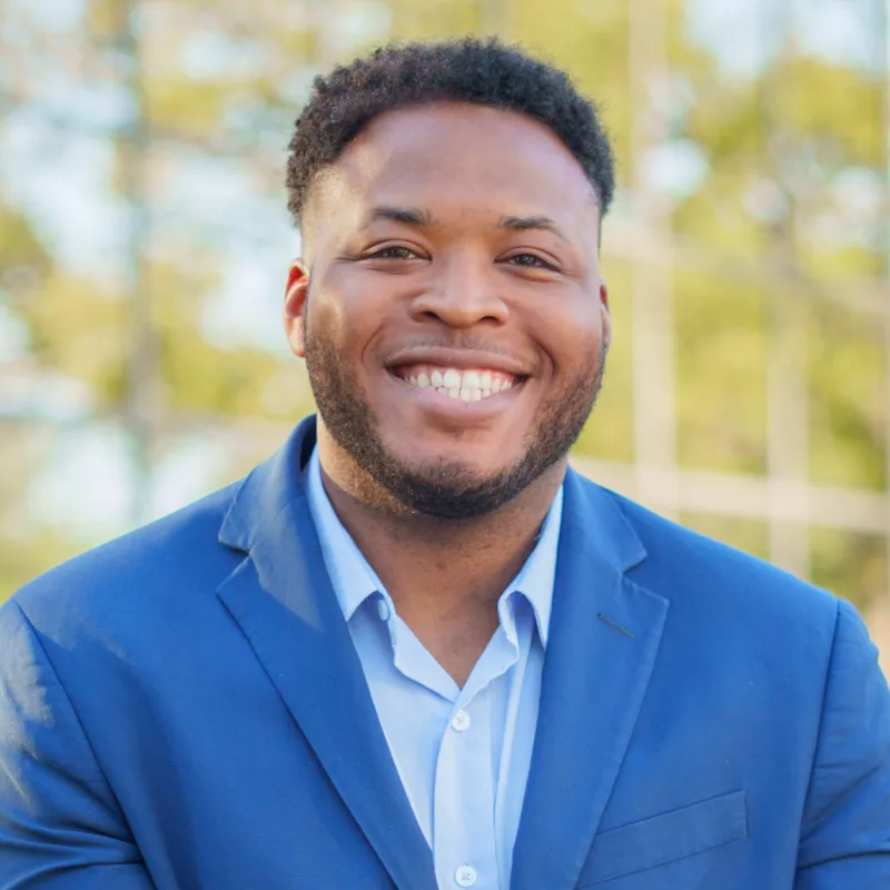 Isaiah Wright, smiling in a blue blazer outdoors